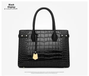 Detail of black embossed crocodile pattern tote bag with gold hardware and shield charm