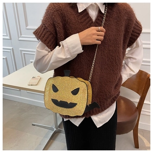 Close-up of golden glitter pumpkin crossbody bag with bat wings and chain strap