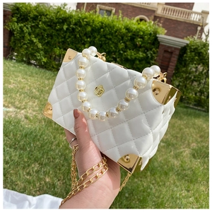 Detail of white quilted crossbody bag with pearl handle and golden camellia flower