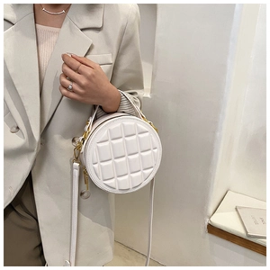 Detail of white quilted round crossbody bag with gold-tone hardware and PU leather texture