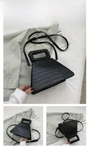Detail view of black crocodile pattern trapezoid bag with gold hardware and top handle