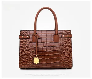 Detail of dark brown tote bag featuring crocodile embossed texture and gold hardware