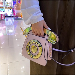 Detailed view of pink retro telephone shaped handbag with golden handset handle and dial