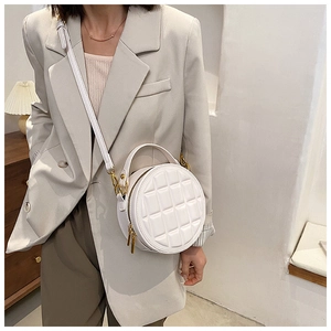 White quilted round leather bag with gold hardware worn as crossbody style