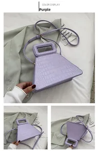 Detail view of purple crocodile texture handbag showing trapezoid shape and handle