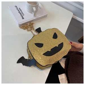 Close-up of sparkling pumpkin crossbody bag with black bat pendant and gold chain strap