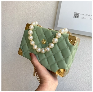 Close-up of mint green quilted leather box bag with pearl handle and metal corners