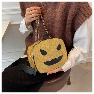 Macro view of sparkly gold sequin pumpkin bag with chain strap and bat charm detail