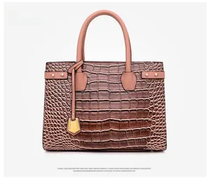 Close-up of pink embossed crocodile skin leather handbag with golden metal hardware and tags