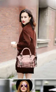 Outdoor street view of a rose gold leather Boston bag with metallic hardware details