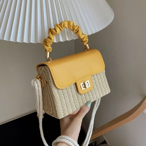 Yellow woven handbag with pleated handle and thick rope shoulder strap in a cozy setting