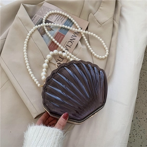 Détail d'un sac à main en acrylique en forme de coquille avec anse en perles