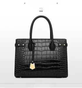 Front view of black crocodile pattern handbag with gold charms and metallic rivets