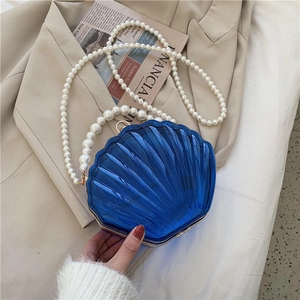 Détail du sac coquillage bleu foncé en acrylique avec poignée en perles et fermoir doré