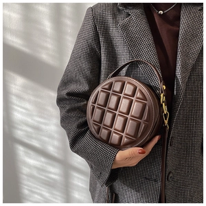 Close-up of deep brown quilted round handbag with 3D grid texture and gold hardware details