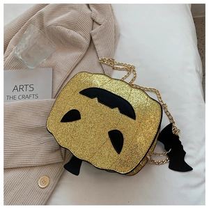 Detail of pumpkin crossbody bag with gold sequins, metal chain, and bat pendant charm