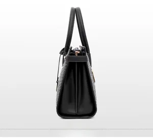 Side view of black handbag showing embossed woven texture and gold-tone metal hardware