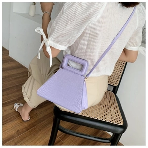 Detail of lavender crocodile-embossed trapezoid bag with hollow handle and slim strap