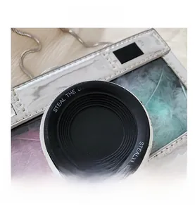 Macro detail of camera-shaped bag with transparent window and colorful feathers