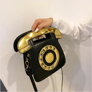 Detail of creative vintage telephone bag showing gold handle and rotary dial design