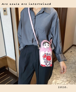 Detail of creative pink Russian doll crossbody bag with floral prints and adjustable strap