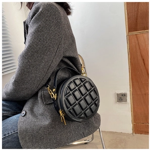 Detail of round black quilted crossbody bag with 3D geometric pattern and gold hardware