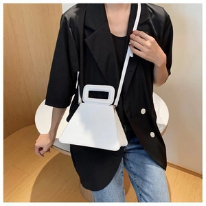 Close-up of white crocodile pattern trapezoid handbag on model in black suit