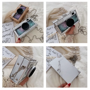 Detail of camera-shaped chain bag featuring mirror finish and internal colorful feathers