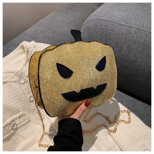 Detail of glittery gold pumpkin crossbody bag with black face and golden chain strap