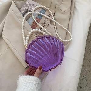 Détail d'un sac coquillage en acrylique violet avec poignée et bandoulière en perles