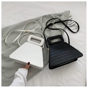 Detail of crocodile embossed leather handbag with hollow rectangular handle in black and white