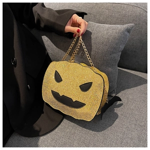 Detail shot of sparkling gold sequined pumpkin bag with a spooky face and chain strap