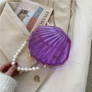 Détail du sac en acrylique violet en forme de coquille avec anse en perles