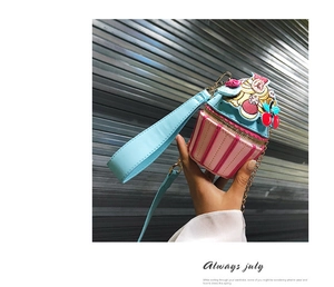 Detail of cupcake shaped crossbody bag with floral embroidery and cherry charm