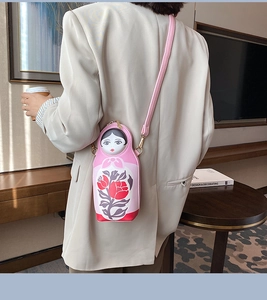 Pink Matryoshka doll crossbody bag with floral prints shown on a model with a beige blazer