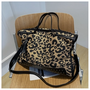Dettaglio della borsa tote leopardata con frange nere, rivetti e finiture in pelle
