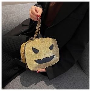 Detail of sequined pumpkin crossbody bag with gold chain and black bat accents