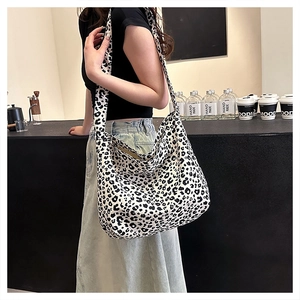 Close-up of leopard print crossbody bag with wide shoulder strap in modern cafe setting