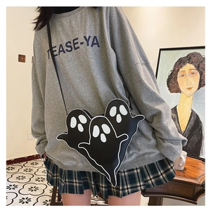Détail d'un sac bandoulière fantôme noir amusant porté avec un sweat-shirt gris