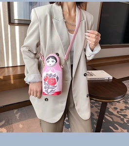 Pink Matryoshka doll crossbody bag with floral patterns worn by model in home setting