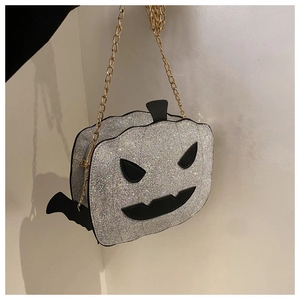 Close-up of silver sequin pumpkin bag with black bat wings and golden chain strap