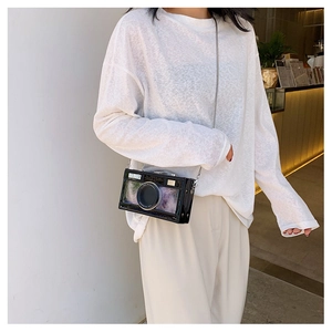 Fashionable camera-shaped crossbody bag with silver chain strap worn by a model