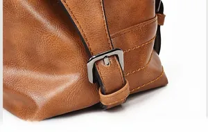 Detail of adjustable silver buckle on brown pebble leather bag with refined stitching