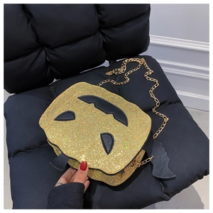 Detailed view of sequined pumpkin bag with bat wings and a golden chain strap
