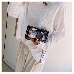 Detail of creative camera-shaped crossbody bag with glossy finish and silver chain strap