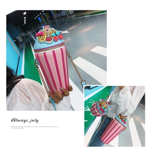 Detail of cupcake-shaped shoulder bag with pink stripes, blue cream top and cherry charm