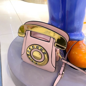 Creative pink vintage telephone shoulder bag with gold dial detail on grey pedestal