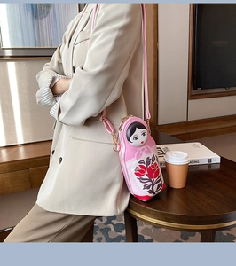 Detail of pink Russian doll crossbody bag with floral patterns and gold metal hardware