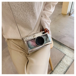 Close-up of camera-shaped bag with silver metallic finish and colorful feather filling