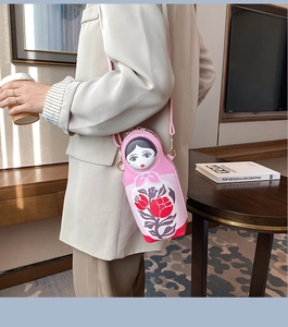 Chic pink Russian Matryoshka doll crossbody bag styled in a cozy indoor setting